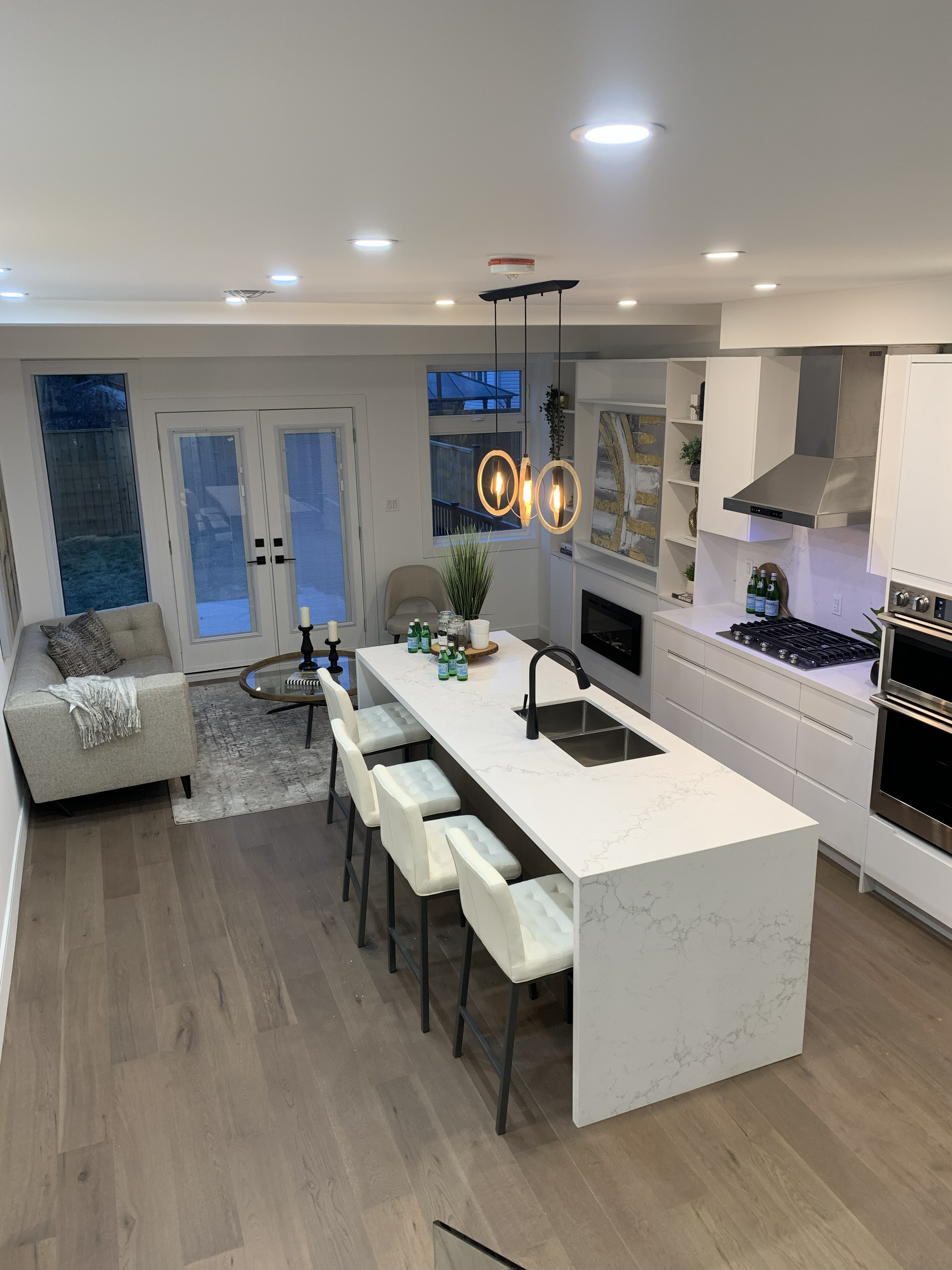 A completed Teamers kitchen with white cabinetry, island, fireplace, and pendant lighting